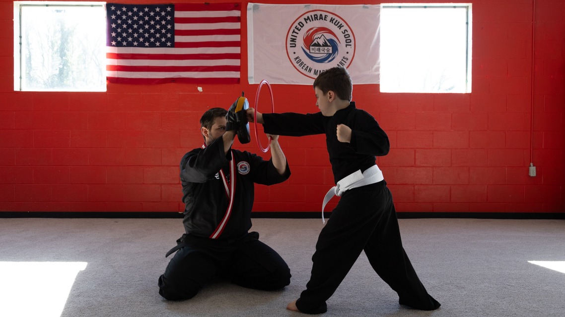 Young Kuk Sool student practices punching accuracy with instructor